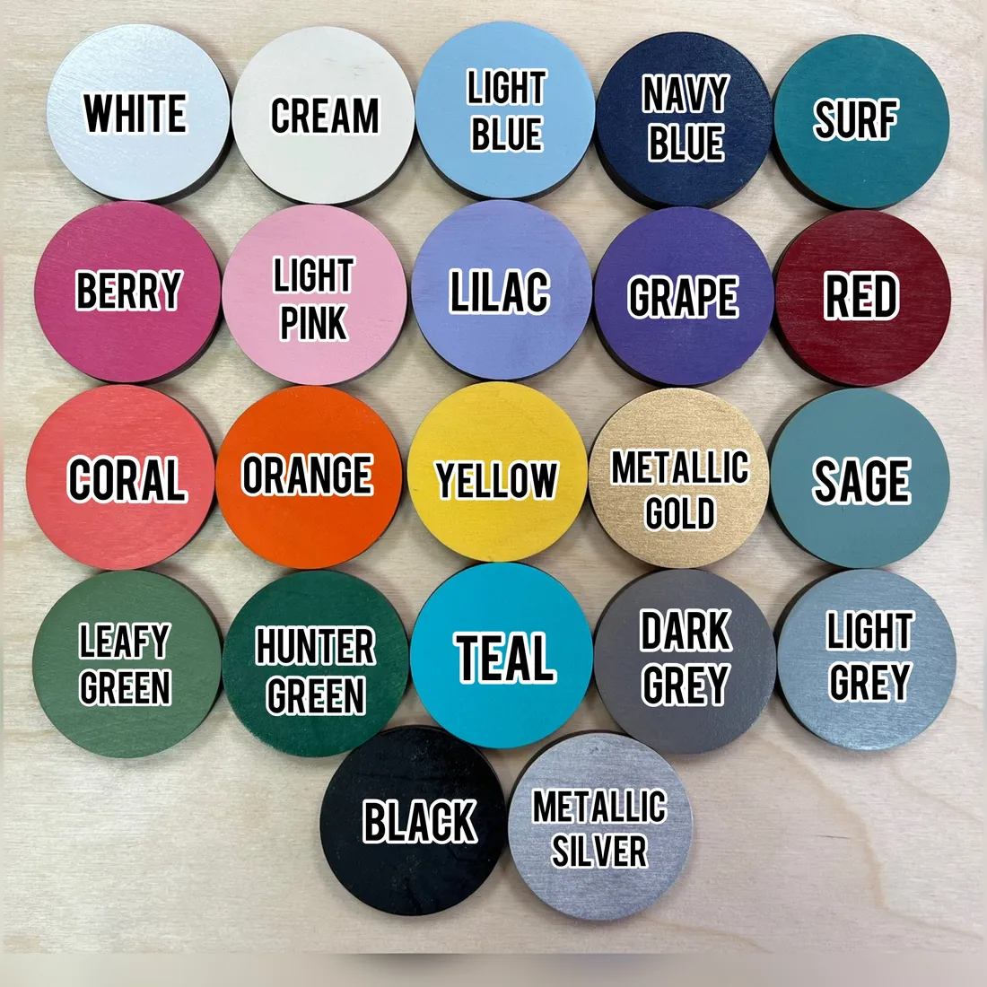 Twenty-two painted wood discs labelled White, Cream, Light Blue, Navy Blue, Surf, Berry, Light Pink, Lilac, Grape, Red, Coral, Orange, Yellow, Metallic Gold, Sage, Leafy Green, Hunter Green, Teal, Dark Grey, Light Grey, Black and Metallic Silver.